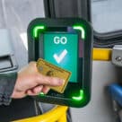 Person tapping an amex card on a MBTA bus payment device