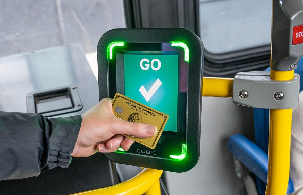 Person tapping an amex card on a MBTA bus payment device